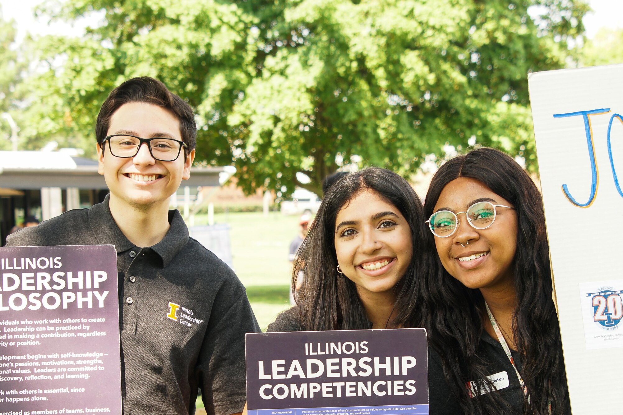 Three student employees holding outreach signs