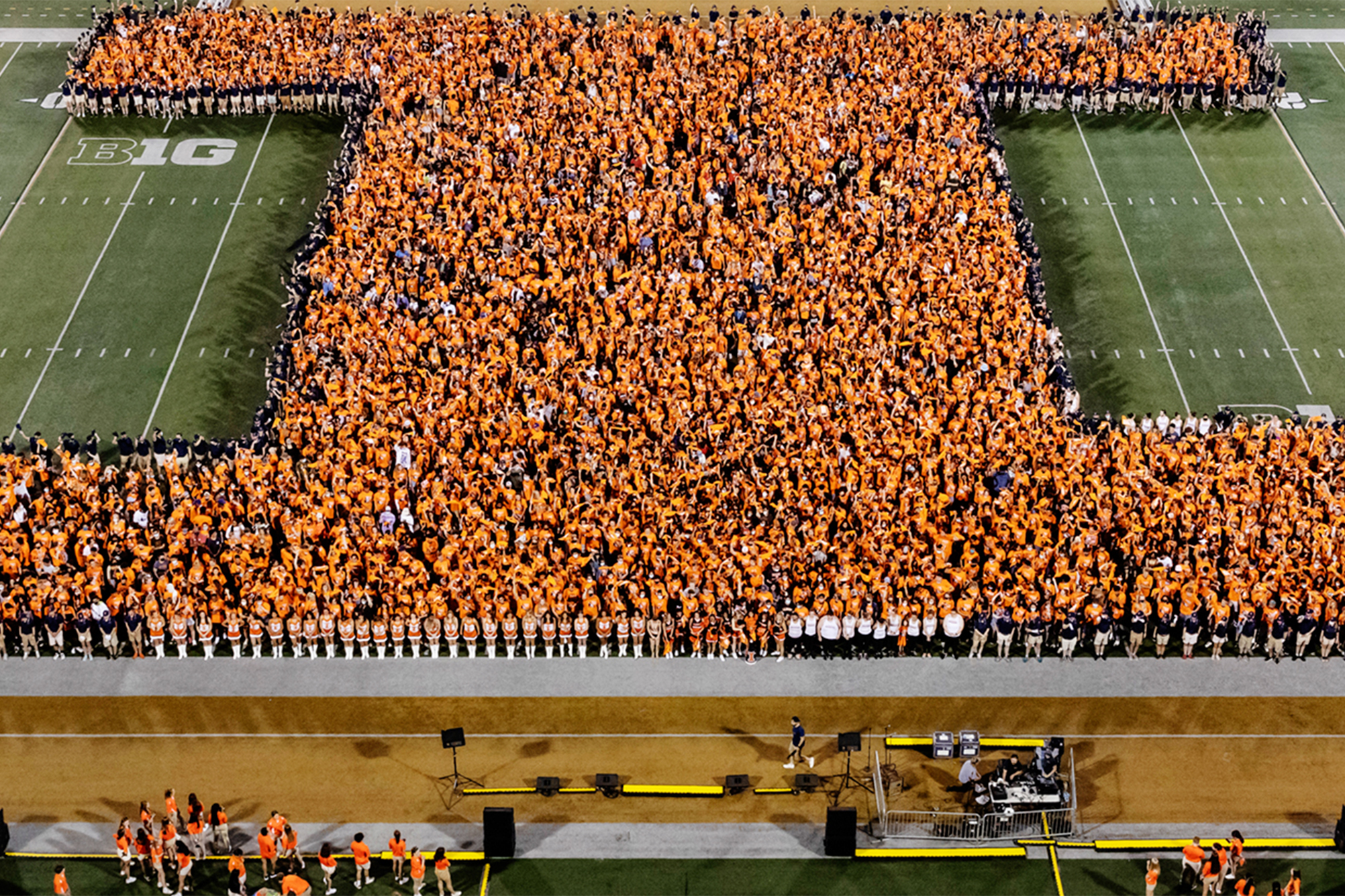 Large group of new students form Block I shape in middle of Memorial Stadium football field