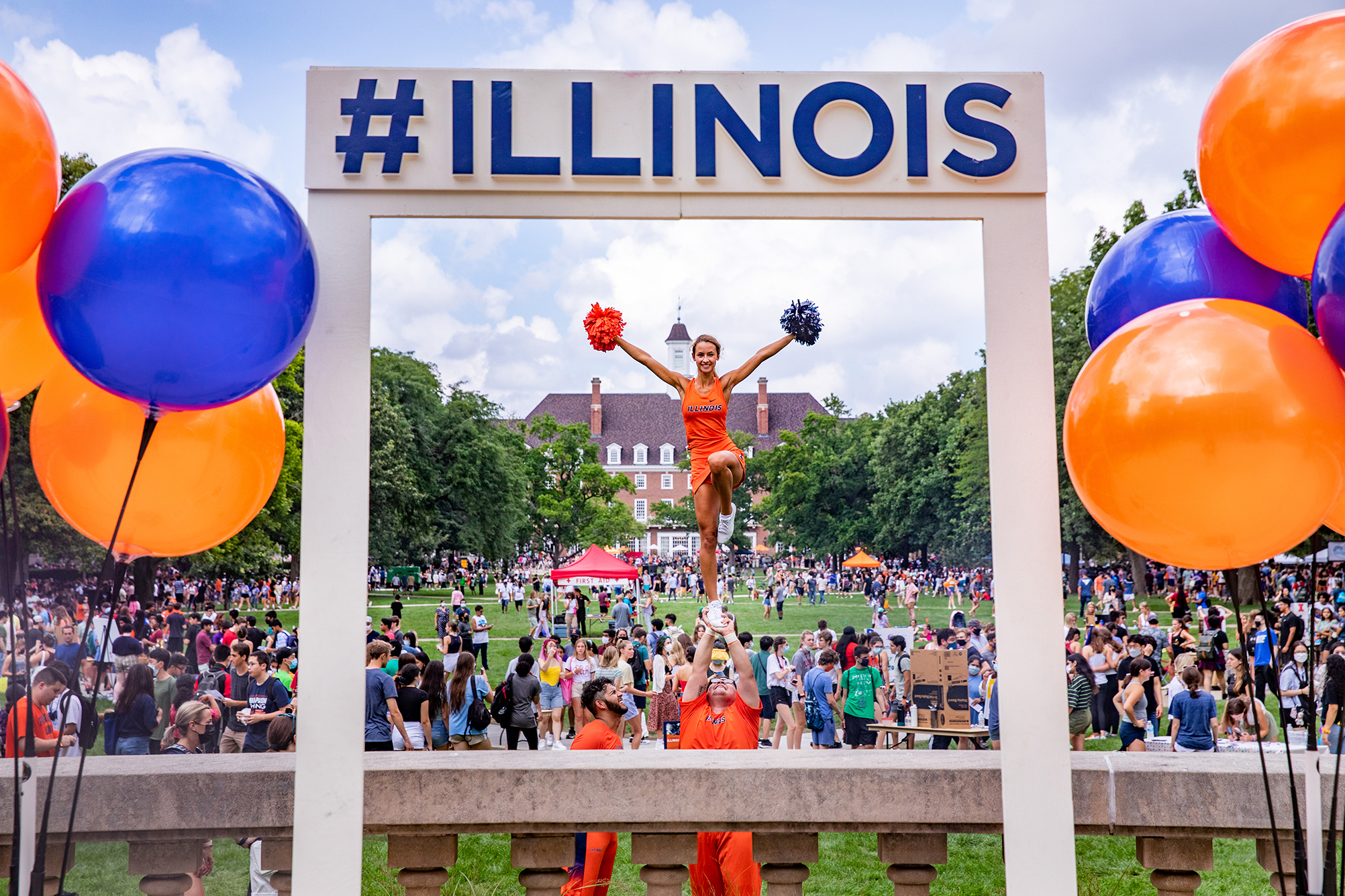 Cheerleaders framed by #Illinois sign overlooking Main Quad with masses of students in background during Quad Day