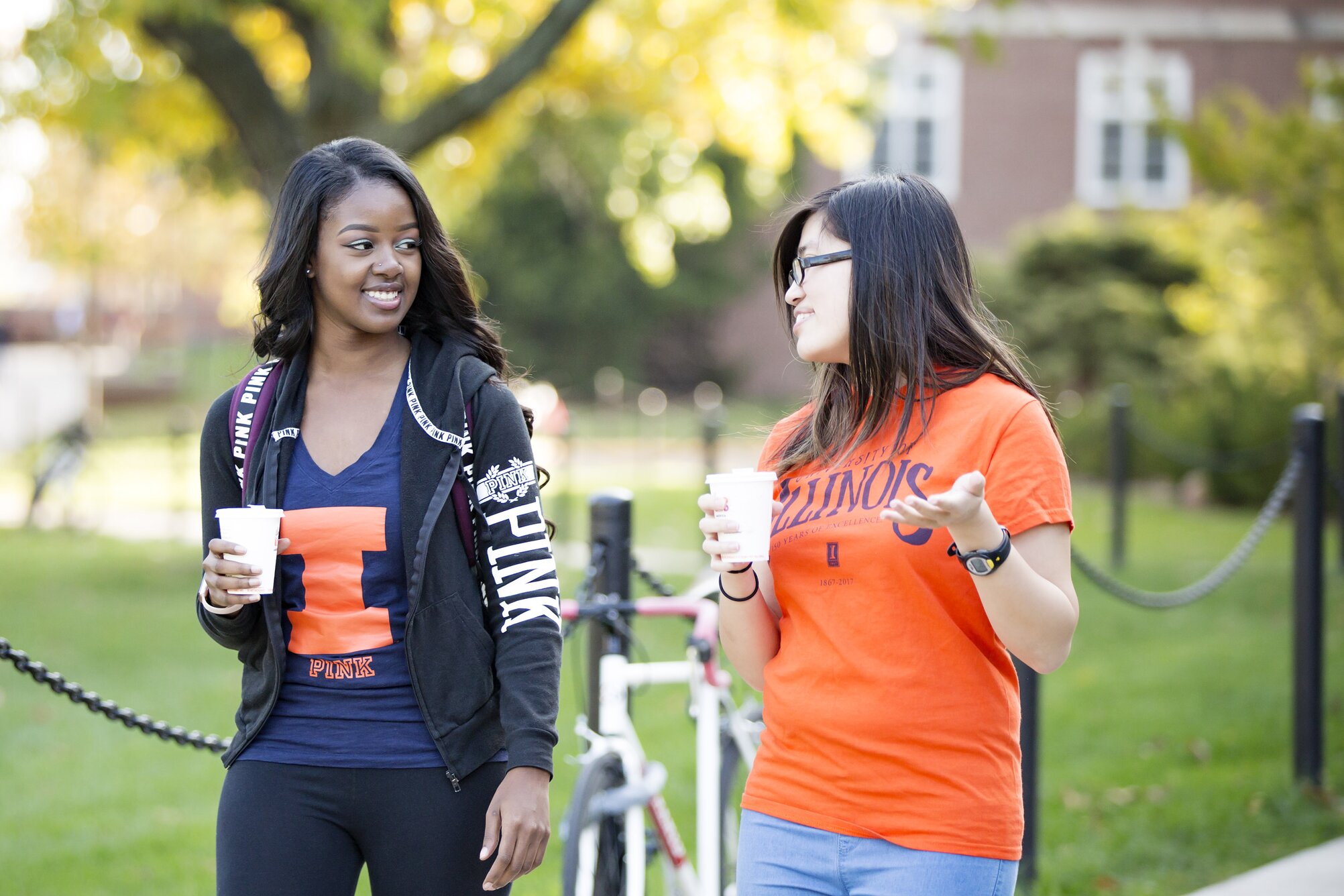 Two female students in Illini gear walking and talking